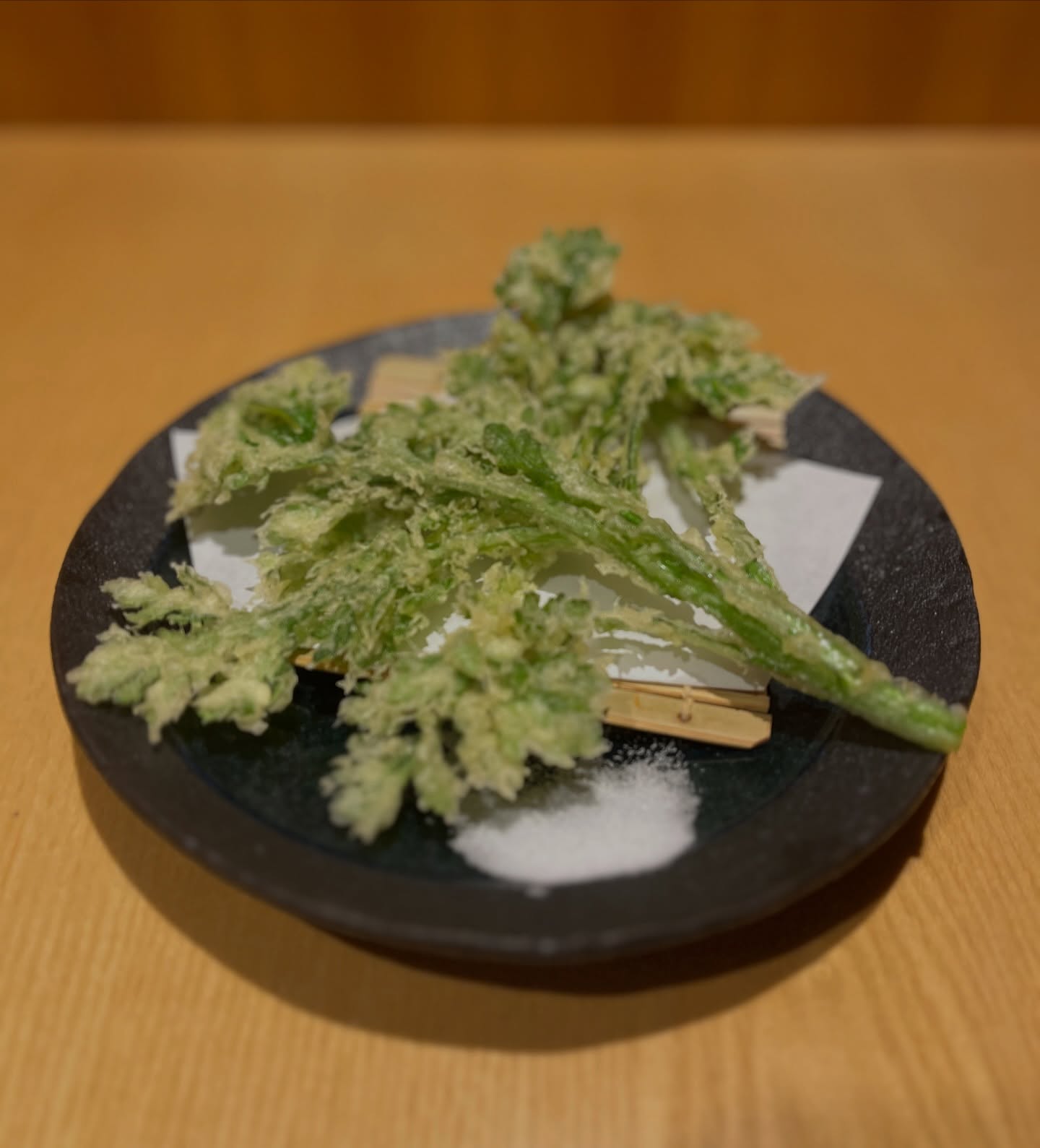 本日は春菊の天ぷらをご紹介‍♀️
揚げることで広がる、春菊特有の香りとほろ苦さ。
サクッと軽く、塩でどうぞ。

住所　港区南麻布4-2-38佑浩寺ビル1階/2階
営業時間　月〜土18:00〜翌5:00
　　　　　　 日祝18:00〜翌3:00

他にも意気な寿し処阿部広尾別館は魅力がいっぱい
️年中無休で思い立ったらすぐ行ける、当日予約も可
️お寿司はもちろん、一品料理のメニューも充実
️深夜営業で大人の時間を満喫
️普段使いにも、ちょっと特別な日にも、カウンター・テーブル・個室とシーンによって使い分けが可能
️高級感がありながら、コストパフォーマンス◎

皆様のご来店心よりお待ちしております‍♀️